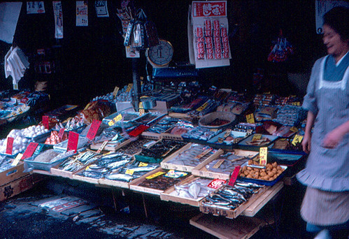 A Kyoto market morning with produce stalls, handwritten signs, and soft daylight.